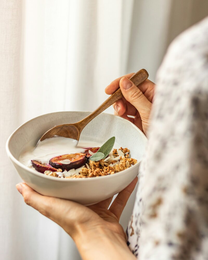 A woman’s hands holding a bowl of fresh, nutritious food, symbolizing the mindful and nourishing approach to health through nutrition coaching.