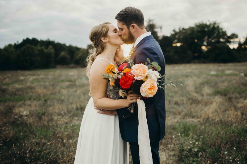 couple kissing in field with flowers