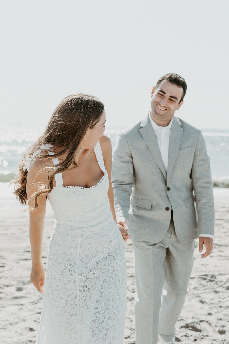 bride and groom walking on beach at their summer wedding in California