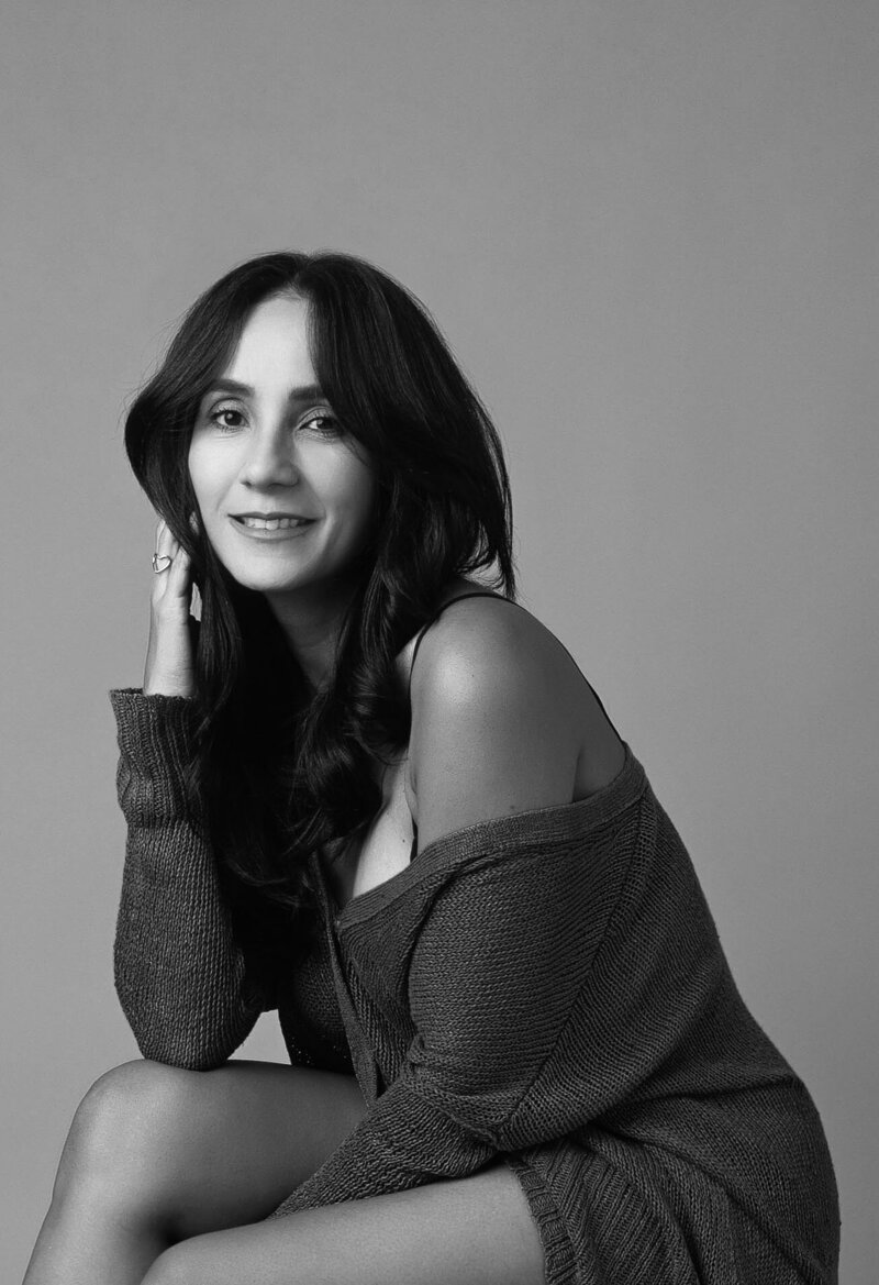woman smiling looking at the camera wearing a black dress in black and white portrait