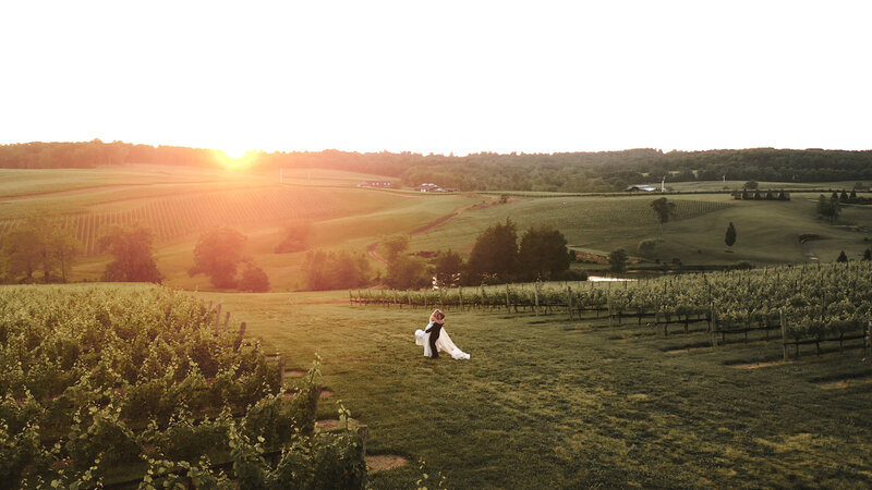 bride and groom running through a vineyard