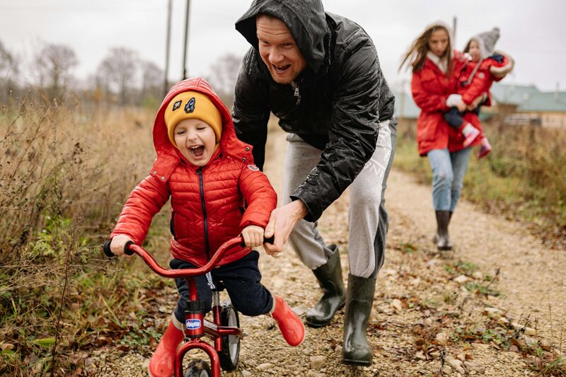 dad running alongside son riding a bike. Kid is smiling and excited