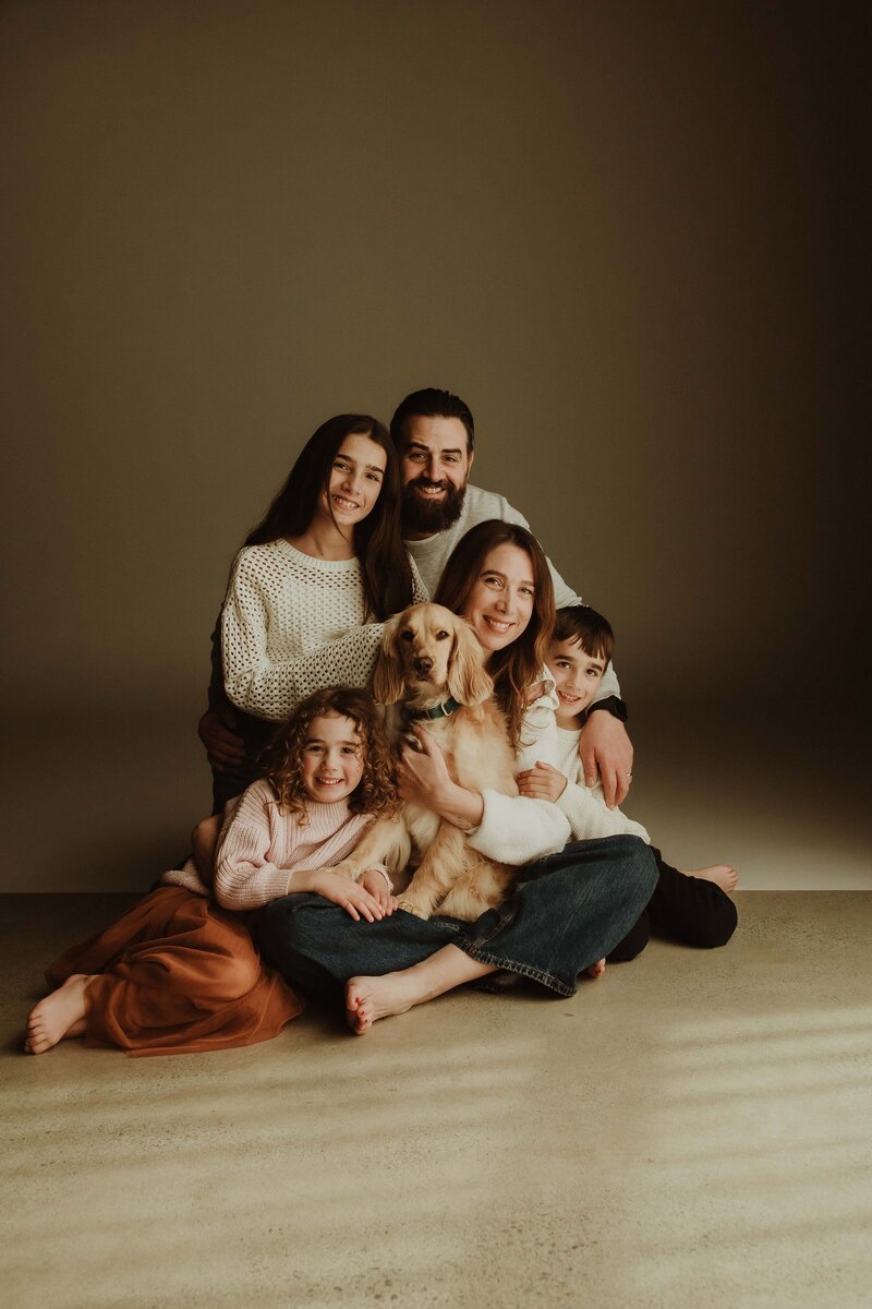 Family with pet dog sitting together in studio, photographed by Sydney family photographer Sophie Lea.