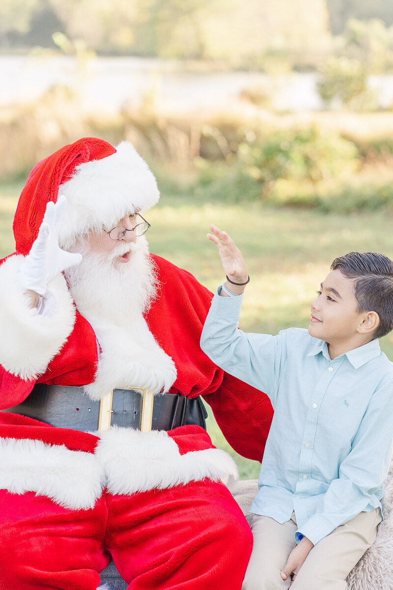 kid doing a fist bump with Santa taken by a Prince William County, Virginia Christmas minis photographer