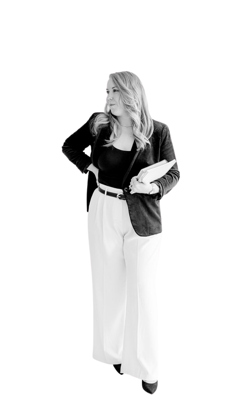 Black and white image of Lizzy Grant standing with hand on hip holding notebooks