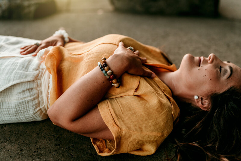 A picture of Danielle laying with her hand on her heart feeling her breath.