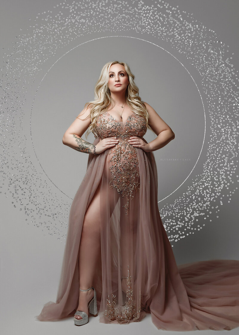 Elegant and glam pregnant mom strong and beautiful in a empowerment pose wearing high heels and a couture client closet gown