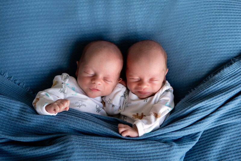 twin newborn boys snuggled under blanket