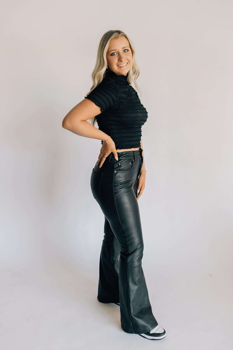 Headshot of certified hair stylist with blond hair extensions smiling wearing black