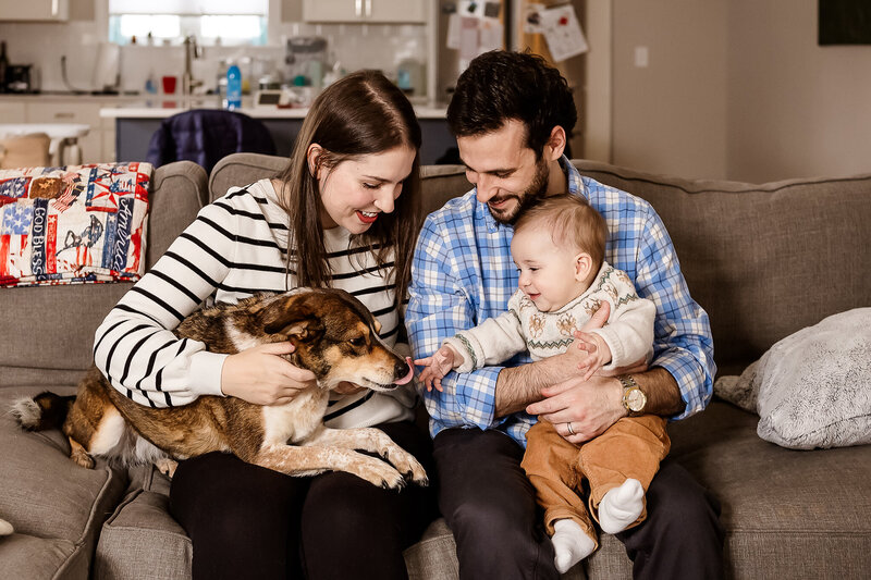 Family sitting on couch with dog licking baby's fingers at in-home family session