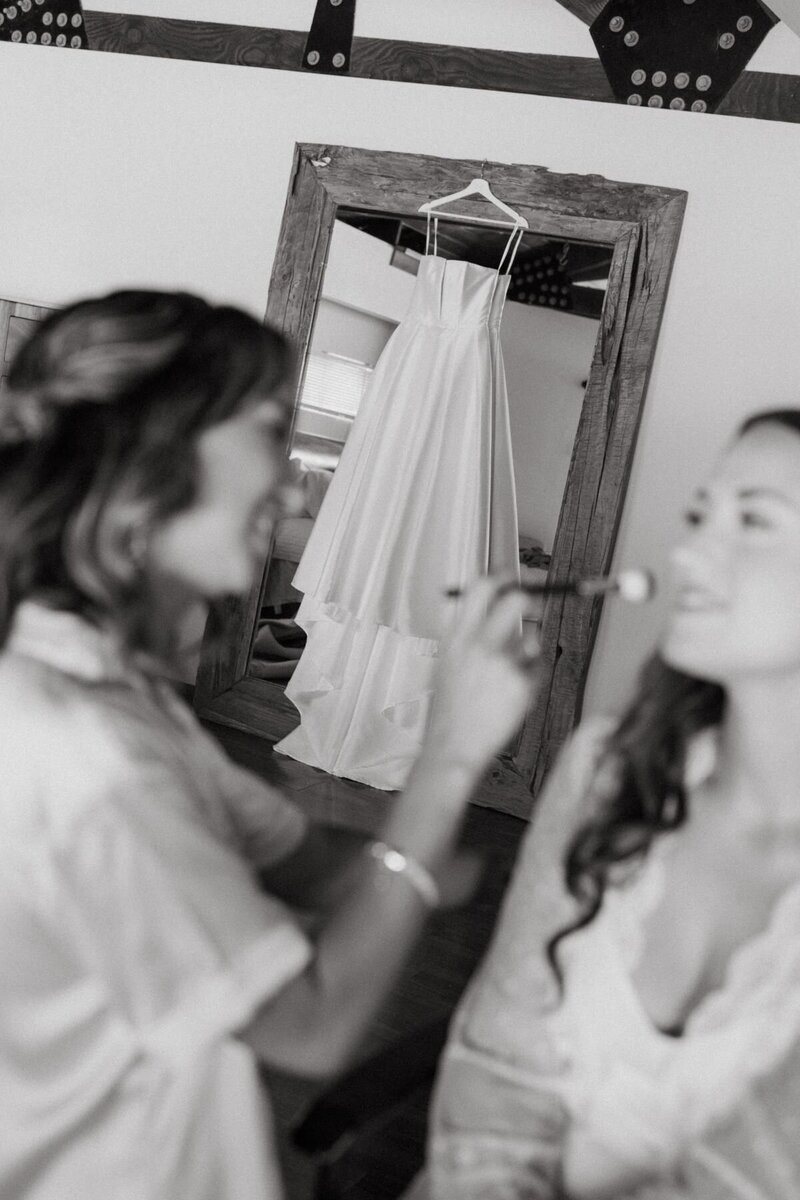 Maid of honor applies bride's makeup, captured by Oahu wedding photographer.