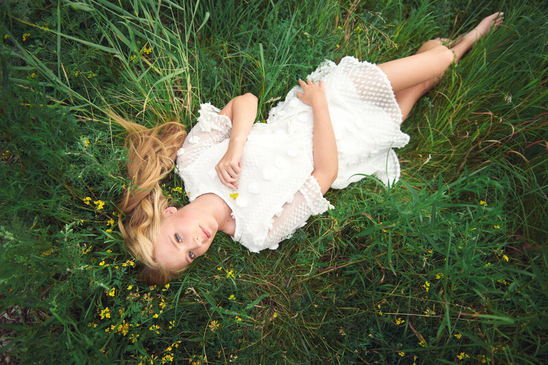 Senior picture in field with yellow flowers and girl in white dress