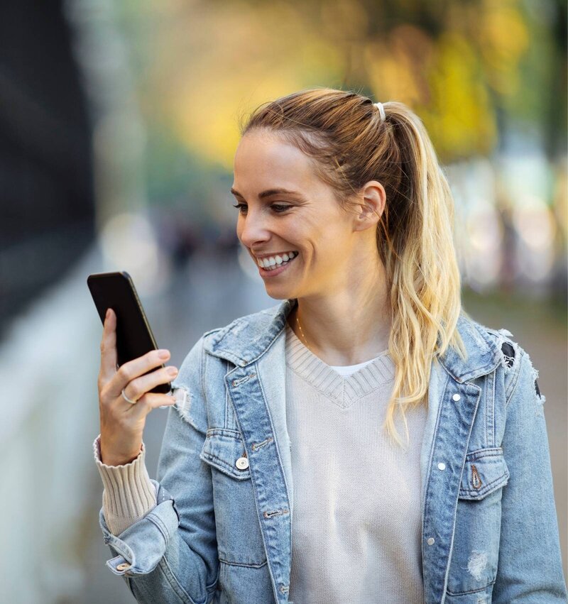 Woman smiling at her phone, representing the Menopause.Rescripted community where women in their 40s & beyond find support and connection.