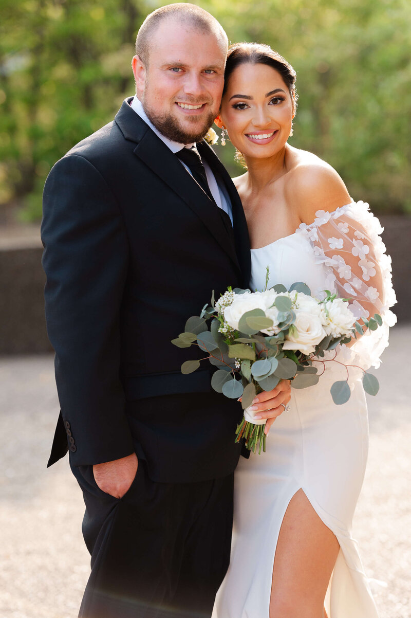 Ottawa wedding photography showing a bride in a short white dress and a groom in a black suit smiling and holding hands outside the NAC wedding venue  in Ottawa.  Taken by JEMMAN Photography