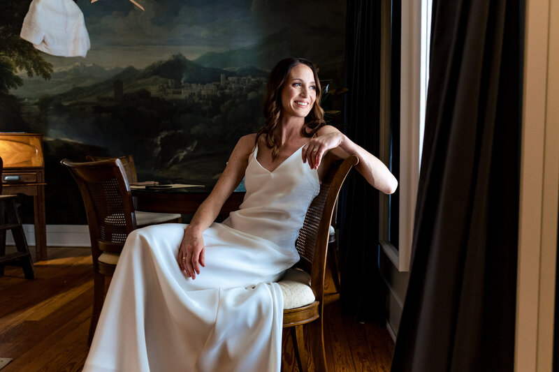A bride sitting in a chair looking out the window at Cornman Farms in Ann Arbor Michigan