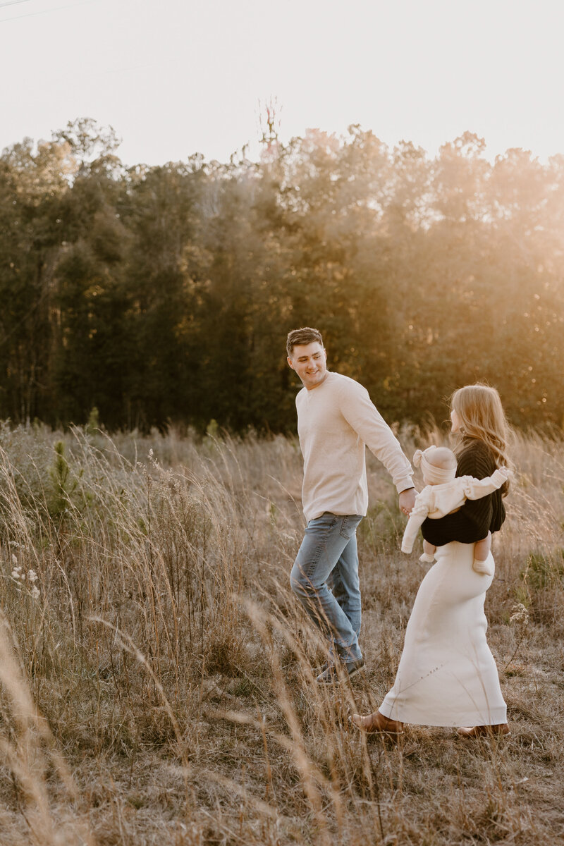 Family walking through a Dothan, AL field at sunset.