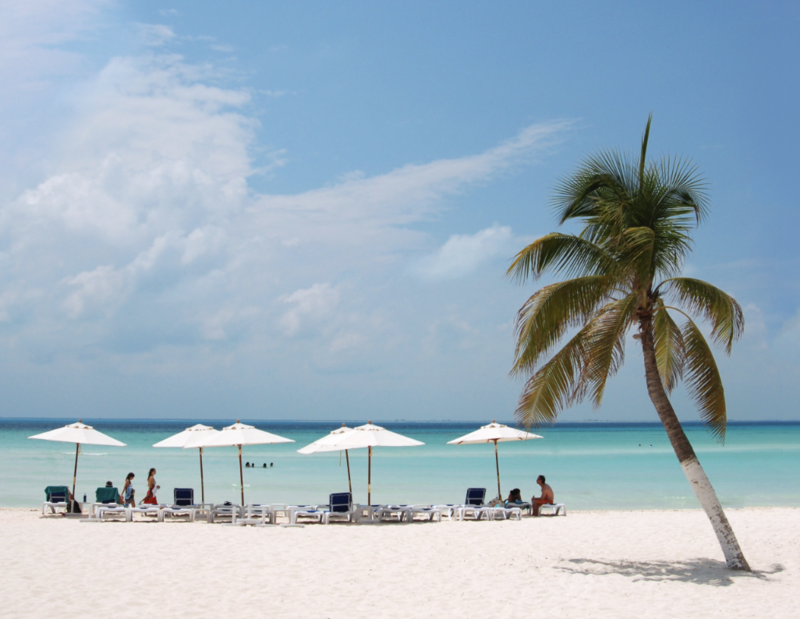 People relax on the white sandy beach under umbrellas