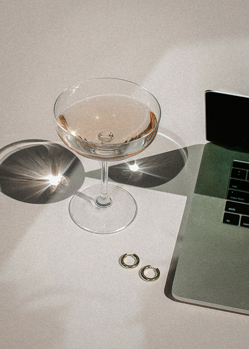 Champagne glass beside a laptop