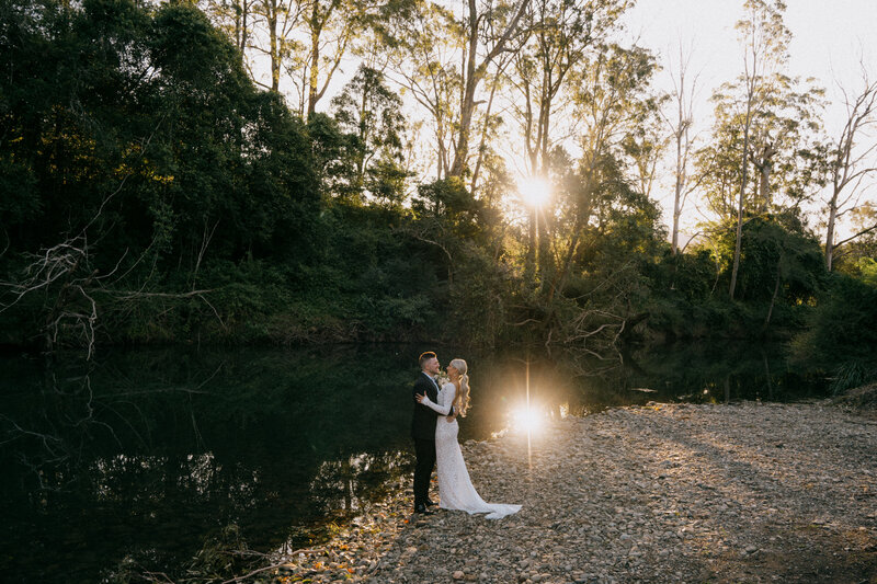 Bride and groom hugging by a river at their Riverwood Downs elopement, Hunter Valley