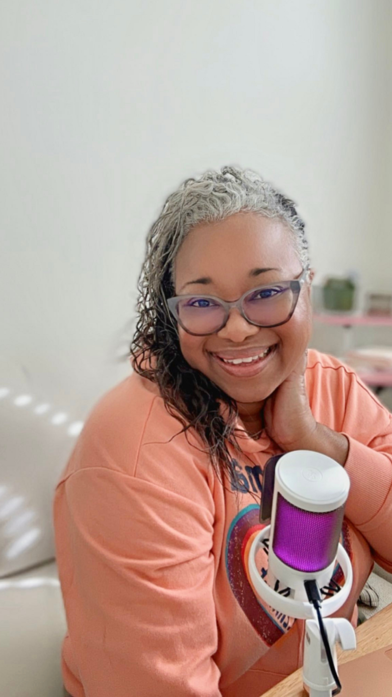 Letitia Hopkins speaking into a podcast microphone as host of the Encourage Over Everything Show, empowering women with self-love, confidence, and Main Character Energy.