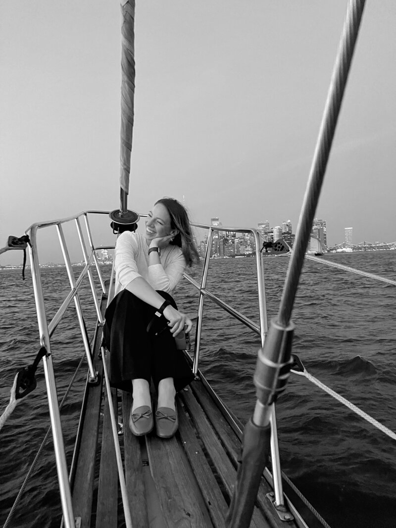 A photographer sits on a sailboat in the hudson during an engagement session in new york city