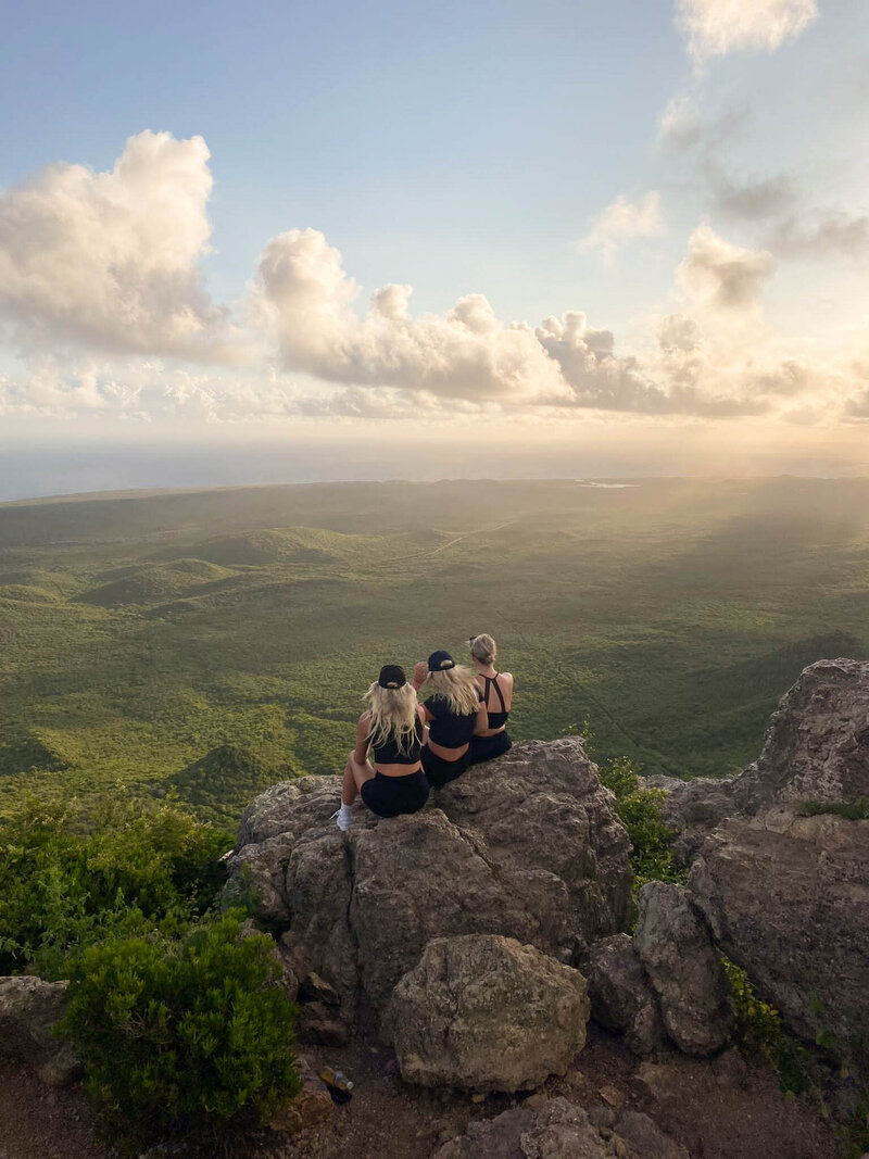 Three girlfriends enjoying a sunset hike on vacation, illustrating the value of expert travel planning. Tailored Oasis Travel Co.