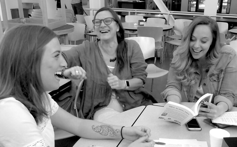 three women laughing with book