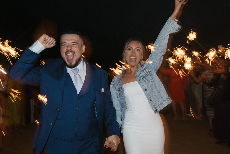 couple running through sparkler exit