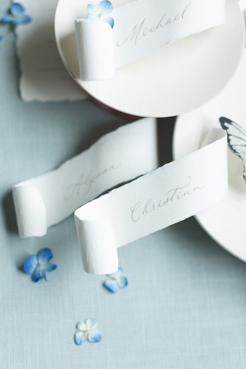 Soft blue linen flat lay mat styled with romantic paper goods and silk ribbon