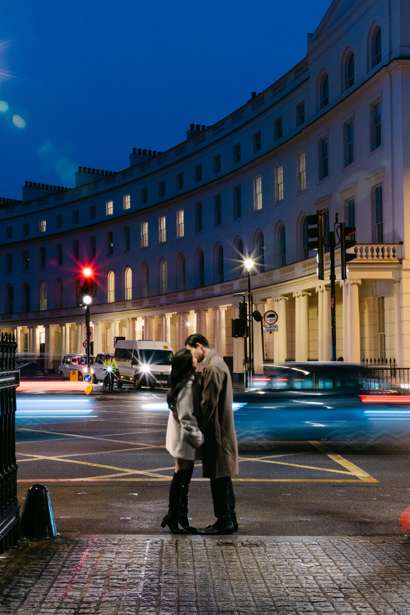 couple embracing at night with traffic going past