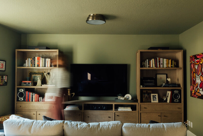 A blurred person in front of a books case, showcasing the interior designer's eclectic home decor.