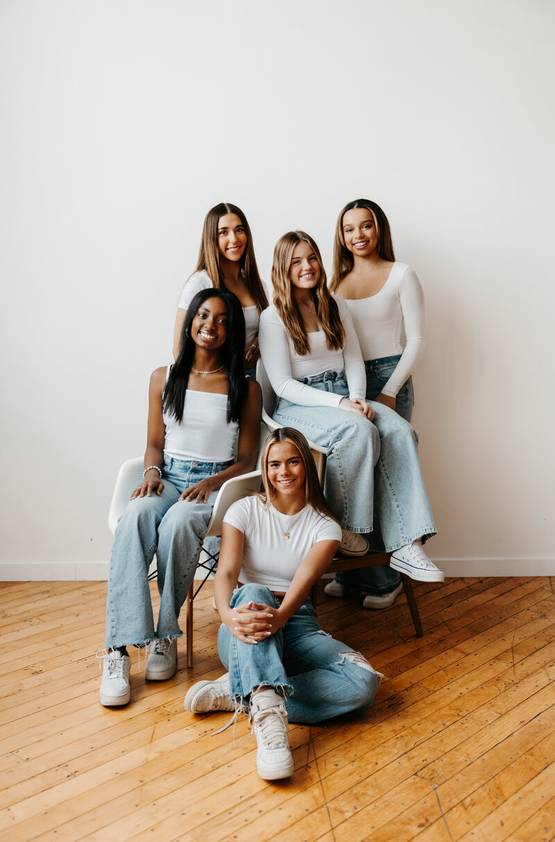 Group of Juma Waganda's senior reps in white tops and blue jeans posing in chairs against a white wall