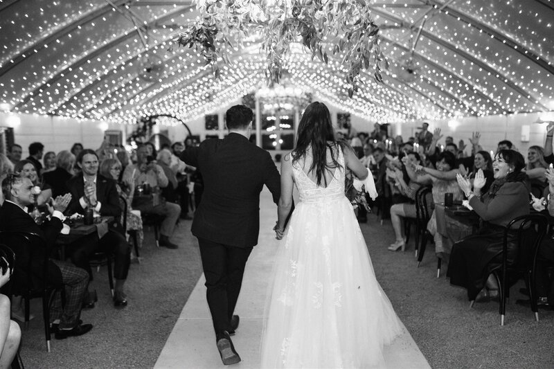 Couple walks down the aisle under twinkling lights at camino real ranch