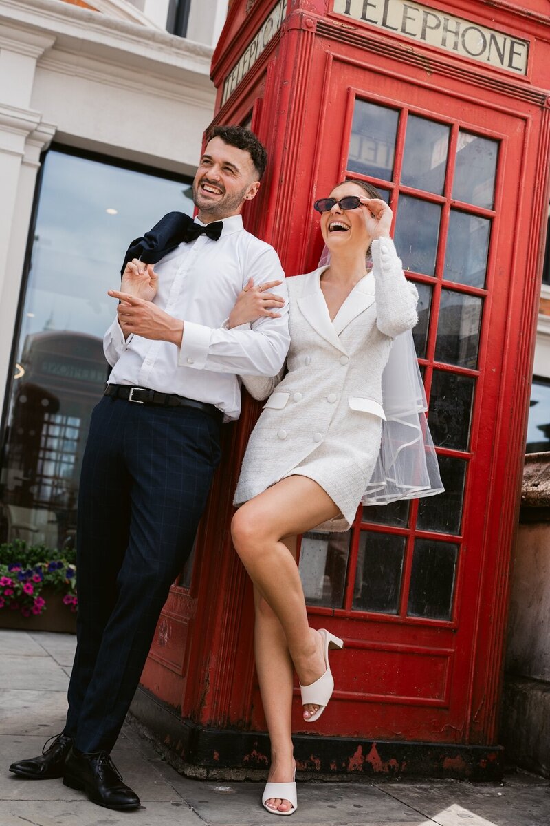 Portrait of a bride and groom after their intimate wedding in London outside a red telephone box