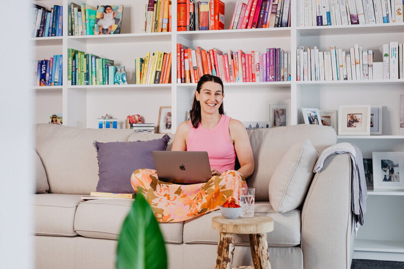 Nutritionist sitting on lounge with laptop in front of book case