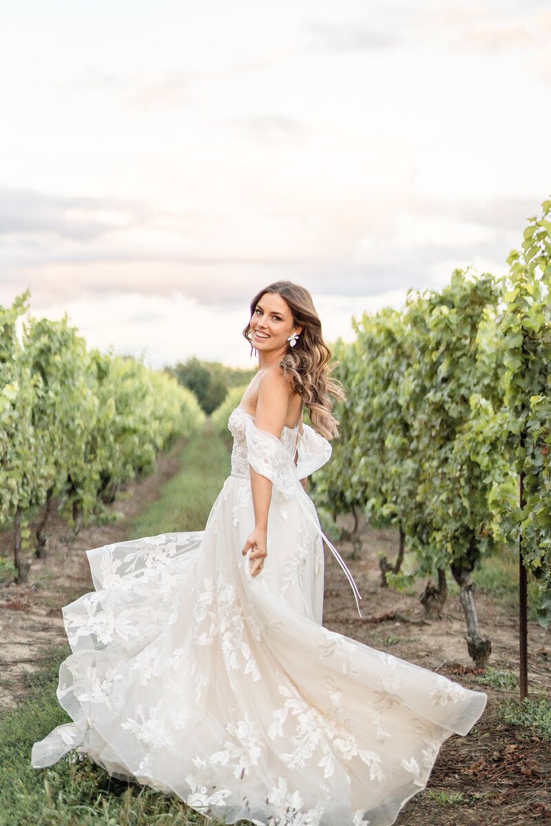 Bride in amalfi coast inspired wedding dress spinning in the rows of vineyards at kurtz orchard