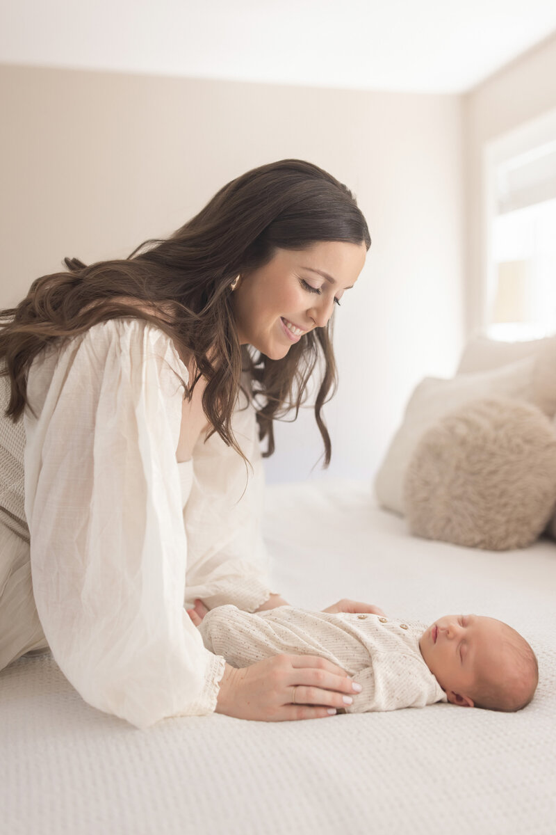 mom kissing newborn head in nursery with dad holding baby