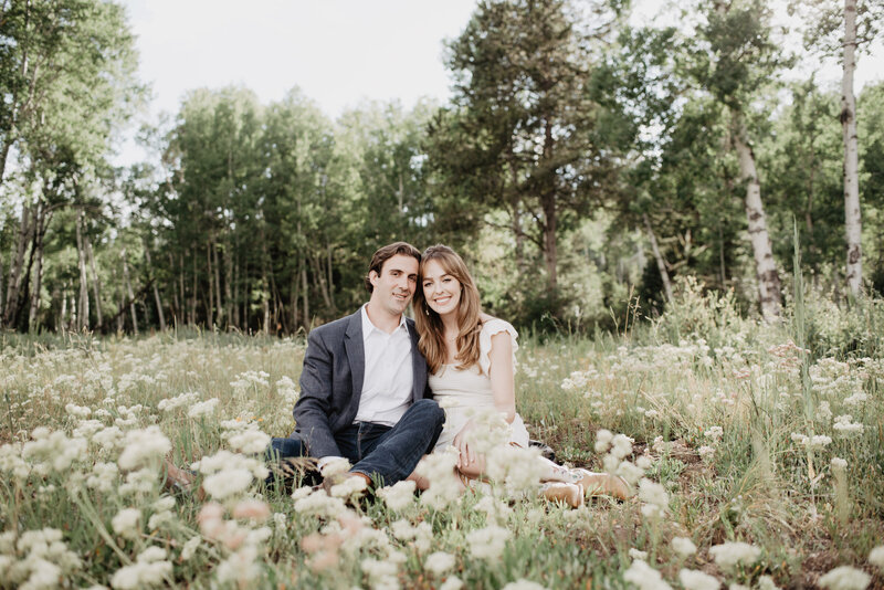 wildflower meadow with bride and groom sitting together for engagemtn pictures in the Grand Tetons captured by jackson hole photographers