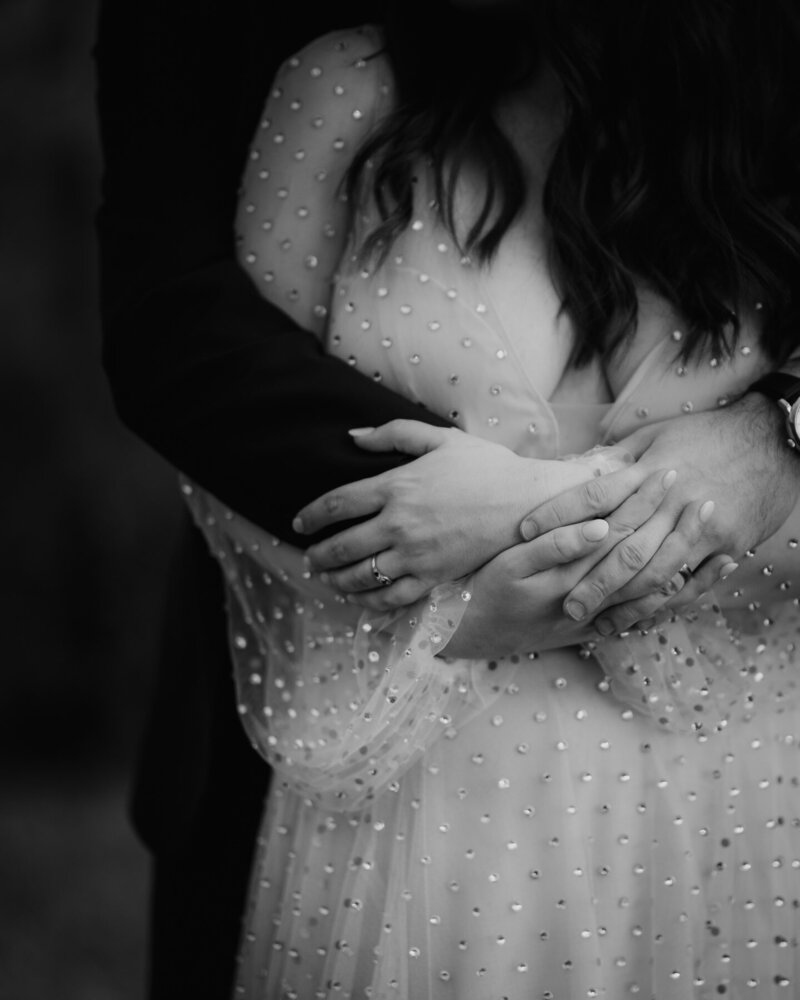 Close up view of bride and grooms hands as they cuddle.