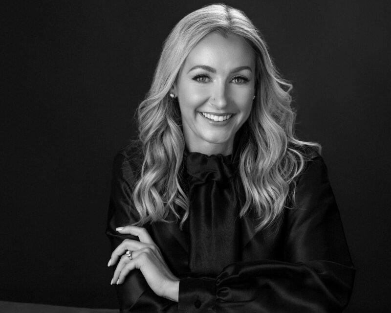 A black-and-white-headshot of a blonde woman smiling