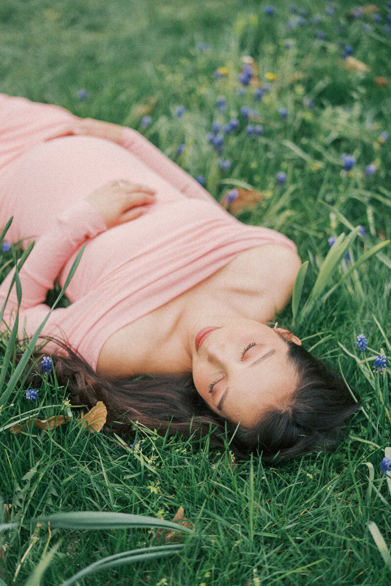 a pregnant woman laying in the grass