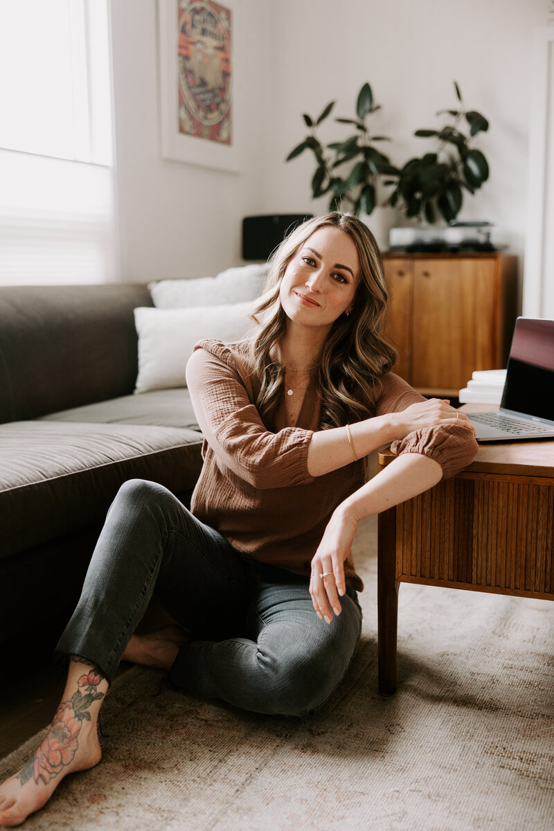 Website copywriter Erika Fitzgerald sitting on the floor with a laptop