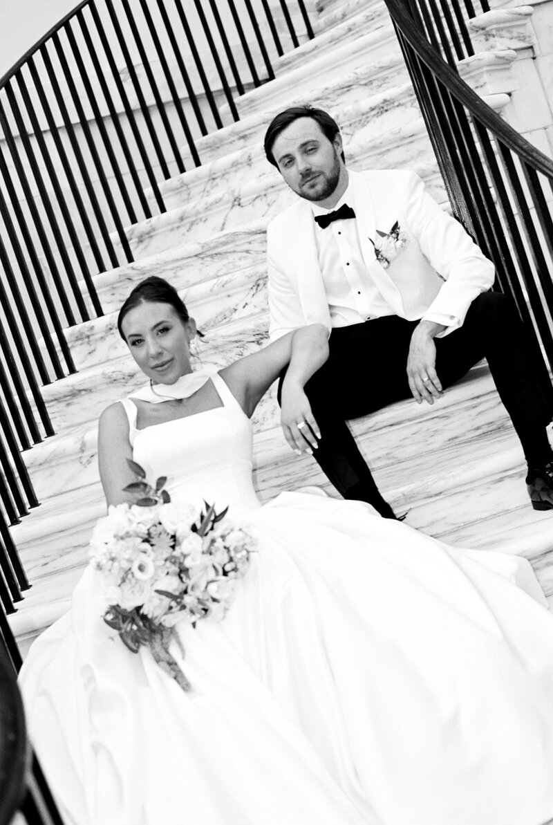 A bride and groom sit on a staircase in downtown charleston SC
