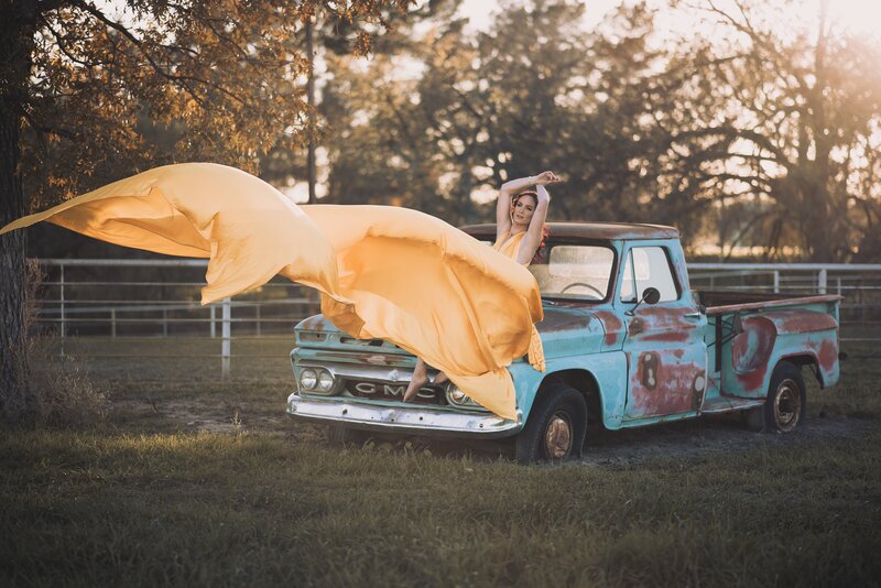 Women Sitting on vintage truck with large yellow flying dress