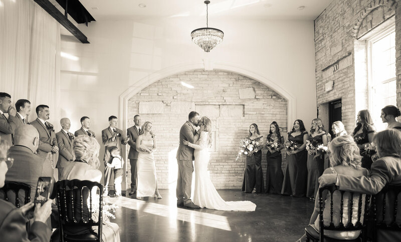 bride and groom kiss at wedding ceremony indoors