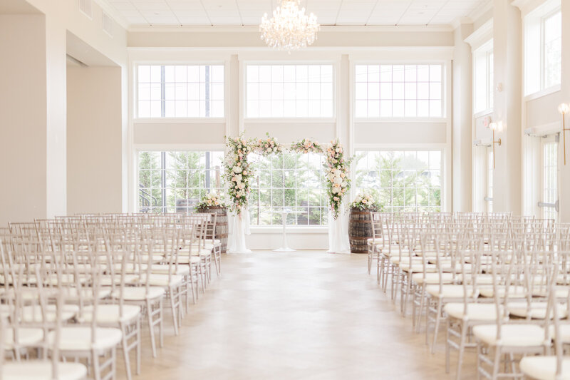 Details of a wedding ceremony set up with white chairs and wine barrels