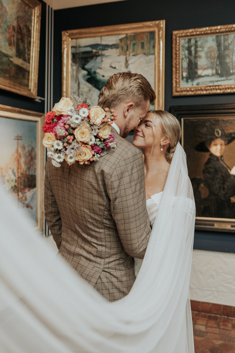 Married Couple posing heads close together surrounded by vintage paintings