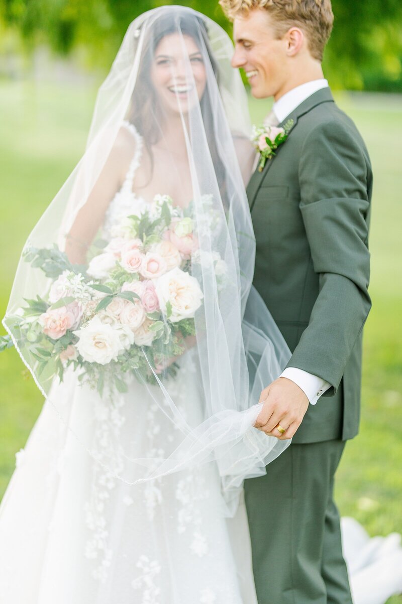 Groom holding veil over bride in Costa Mesa, California.