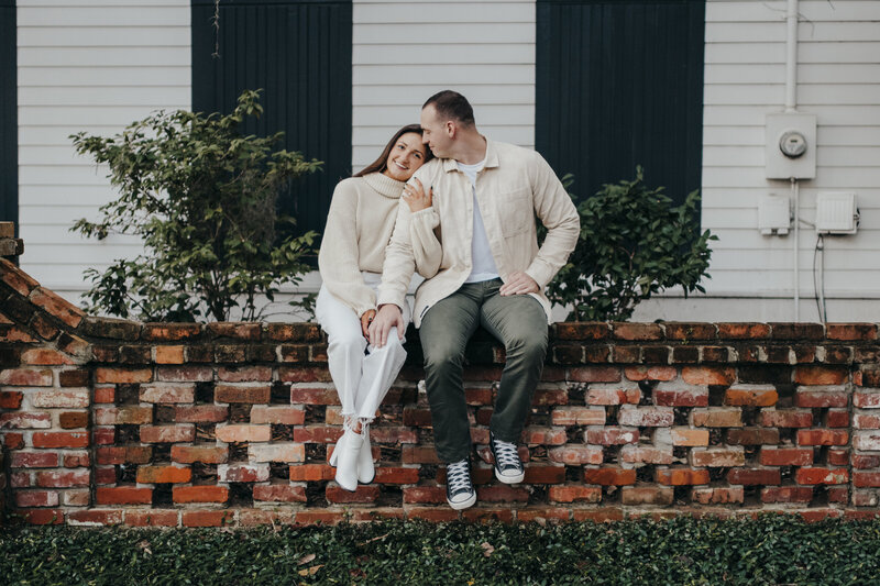 couple sitting on brick wall for old town buffton engagement session