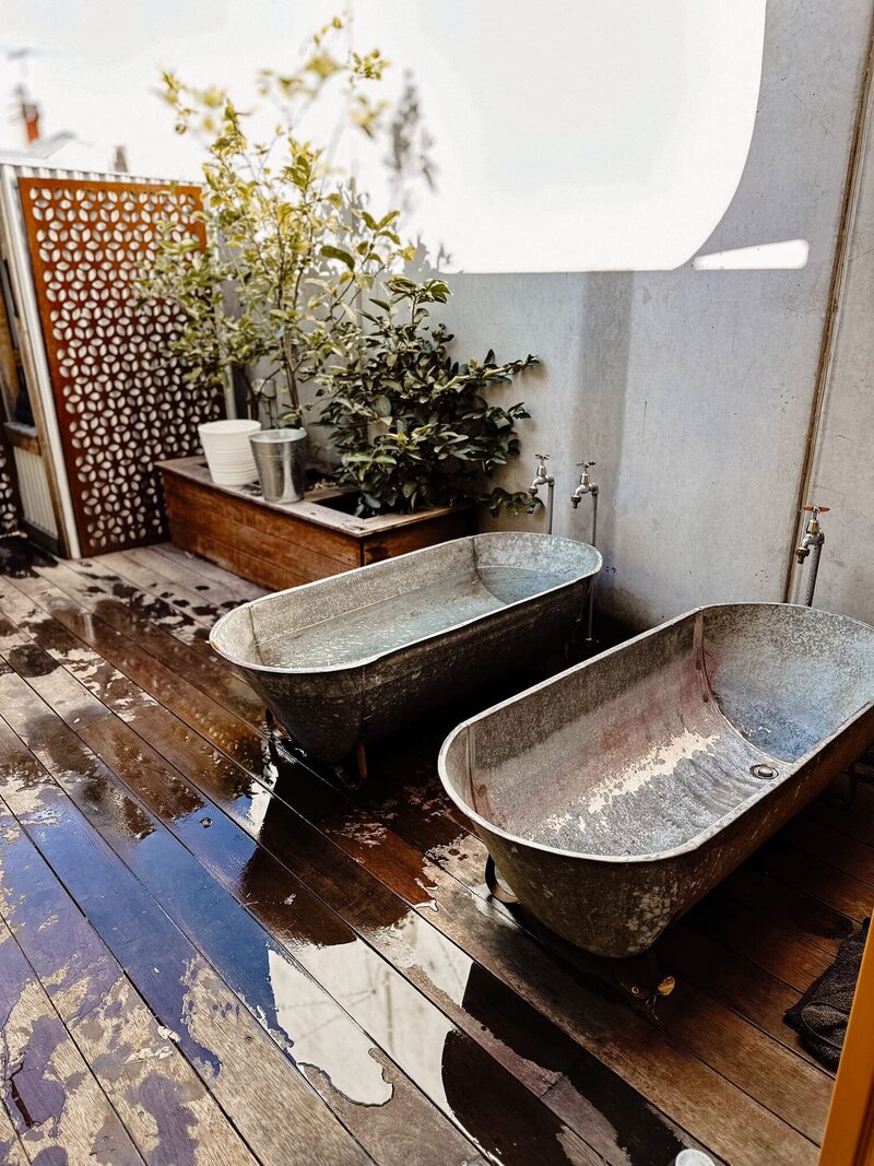 Two ice baths in an outdoor area at a Collingwood gym, surrounded by plants.